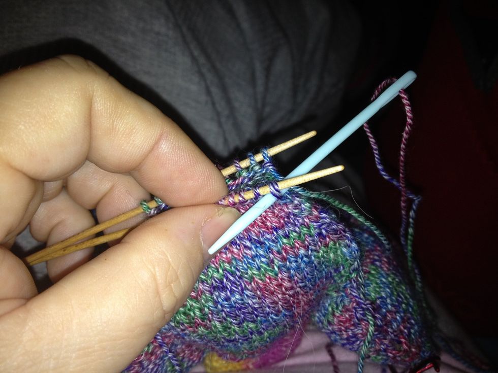 Thread working yarn onto tapestry needle. Bring through 1st stitch on front needle purlwise -- as if you would purl the stitch. Pull yarn through--not too tightly--but leave stitch on knitting needle.