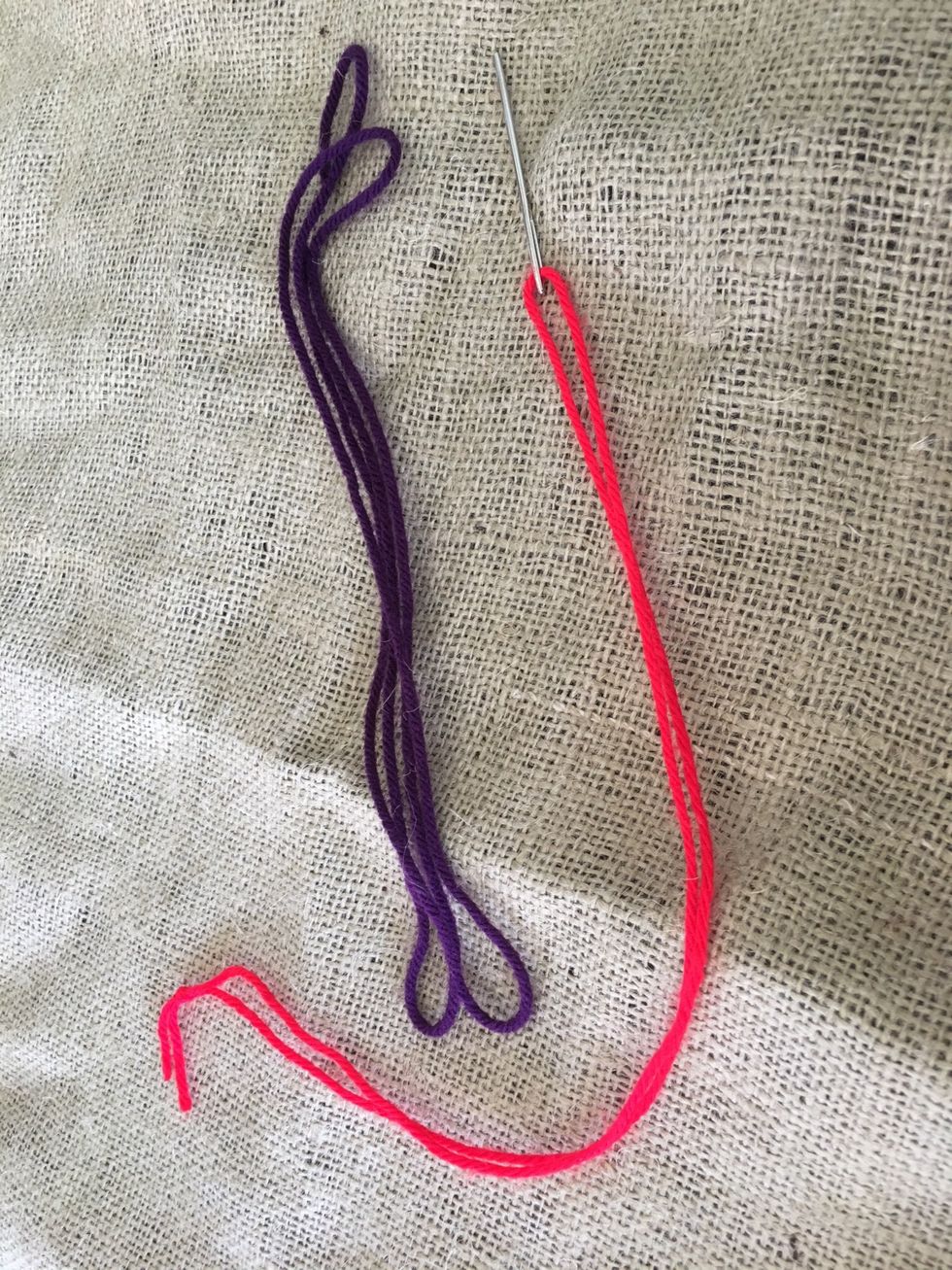 Threaded needle, second color of thread, fabric.