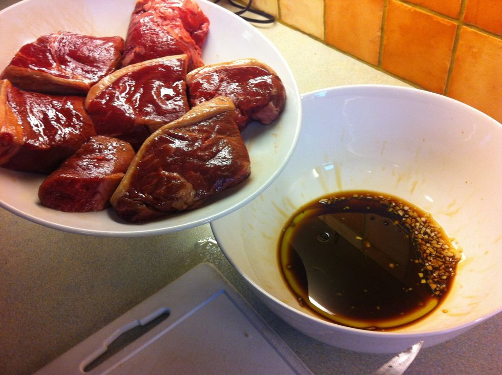 Throw in the garlic then pour an equal amount of Olive oil & Soy sauce into a deep bowl or dish, (enough to cover the steaks)