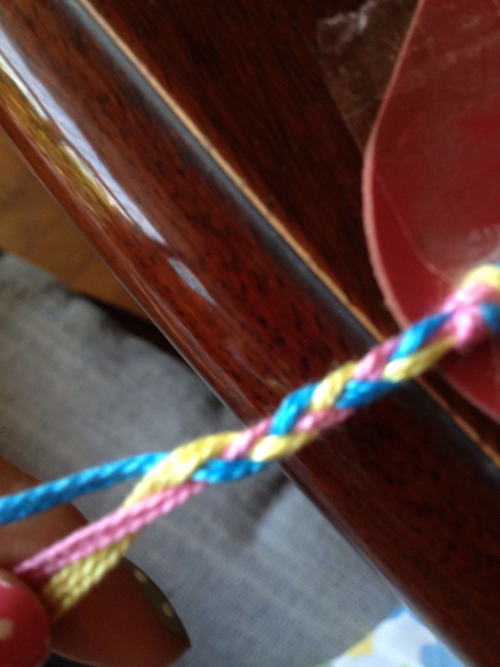 Tide all 3 pastel colors together, tie it up and put the tape at the knot with the table. Braiding pastel rope!