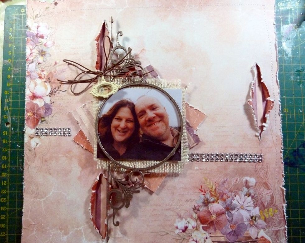 Tie 2 bows with the cord, one looping the Vintage trinket on whilst tying. Stick the bows on top of each other as shown. Cut thin strips of the crystal bling & stick a piece each side of photo layers.