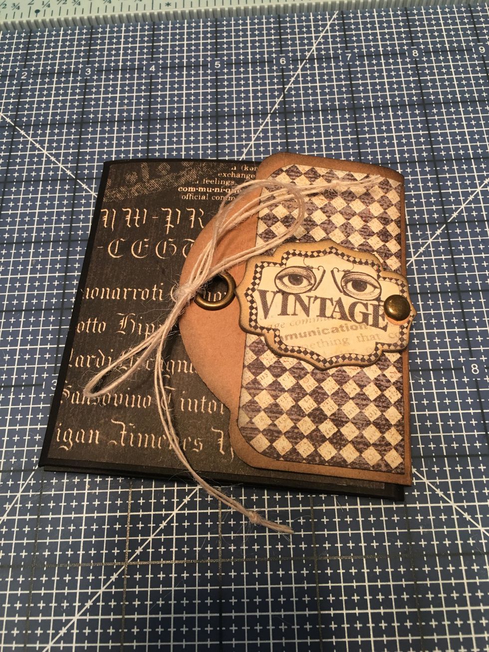 Tie a double button string through the grommet on the outside and tie into a bow. Secure the knot with a bit of glue so it does not come untied. Tie knots in the ends of the string.