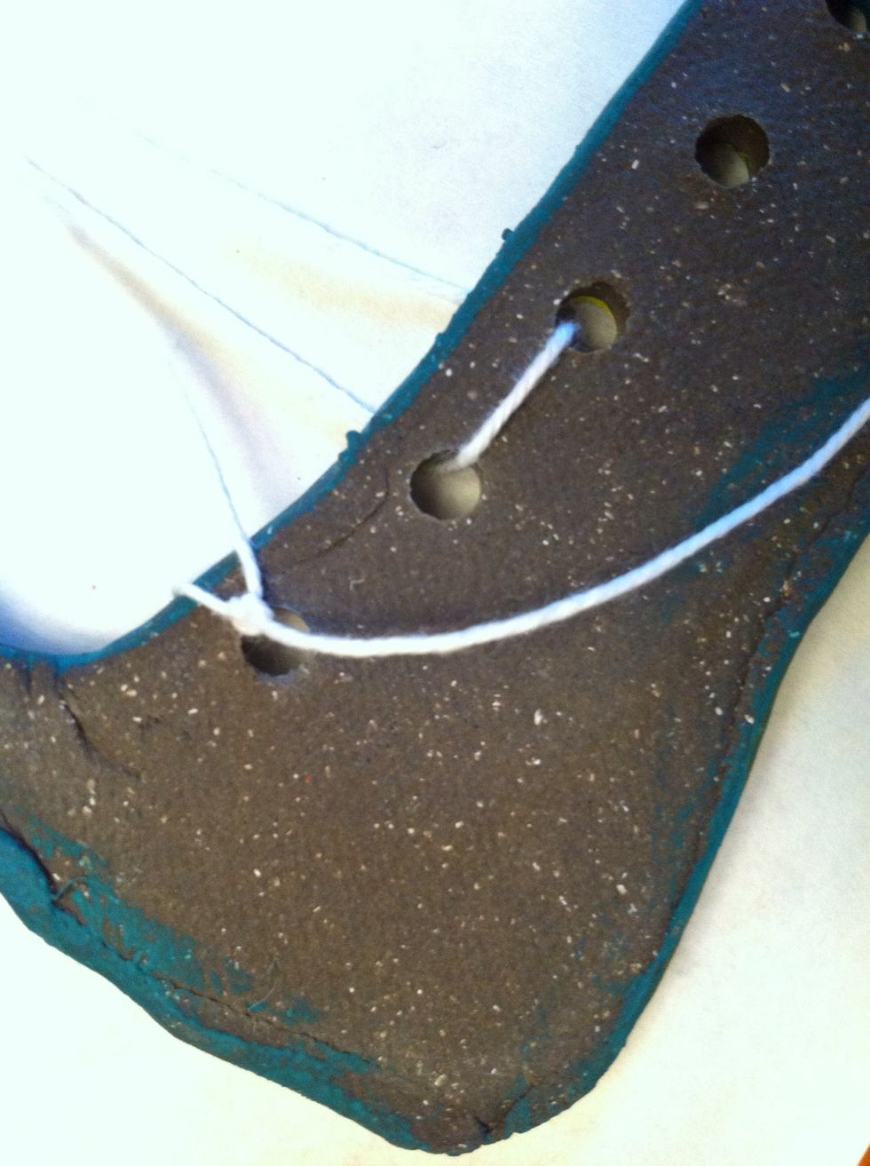 Tie a knot around the first hole to secure the string.