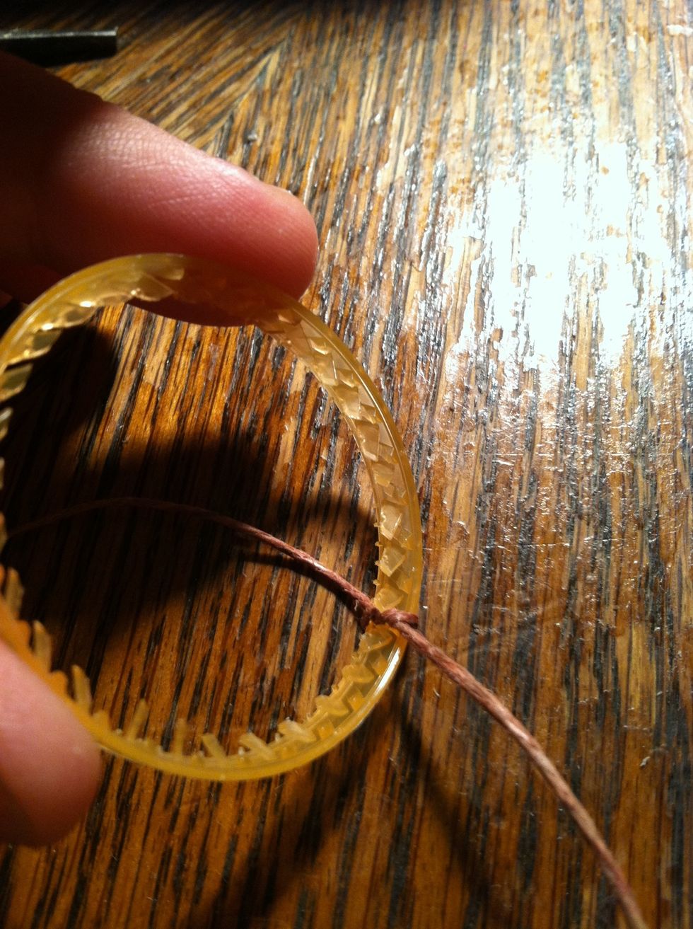Tie a knot around your ring on the inside like this. Have about equal lengths of string on either side.