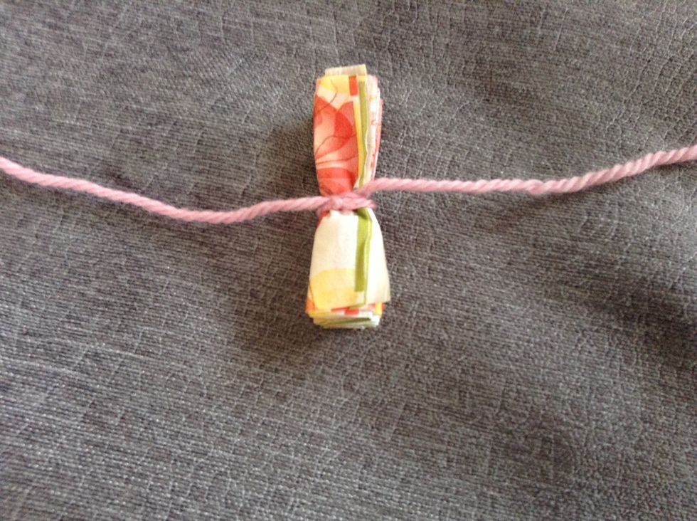 Tie a knot in the middle of the " harmonica" looking napkin with the yarn