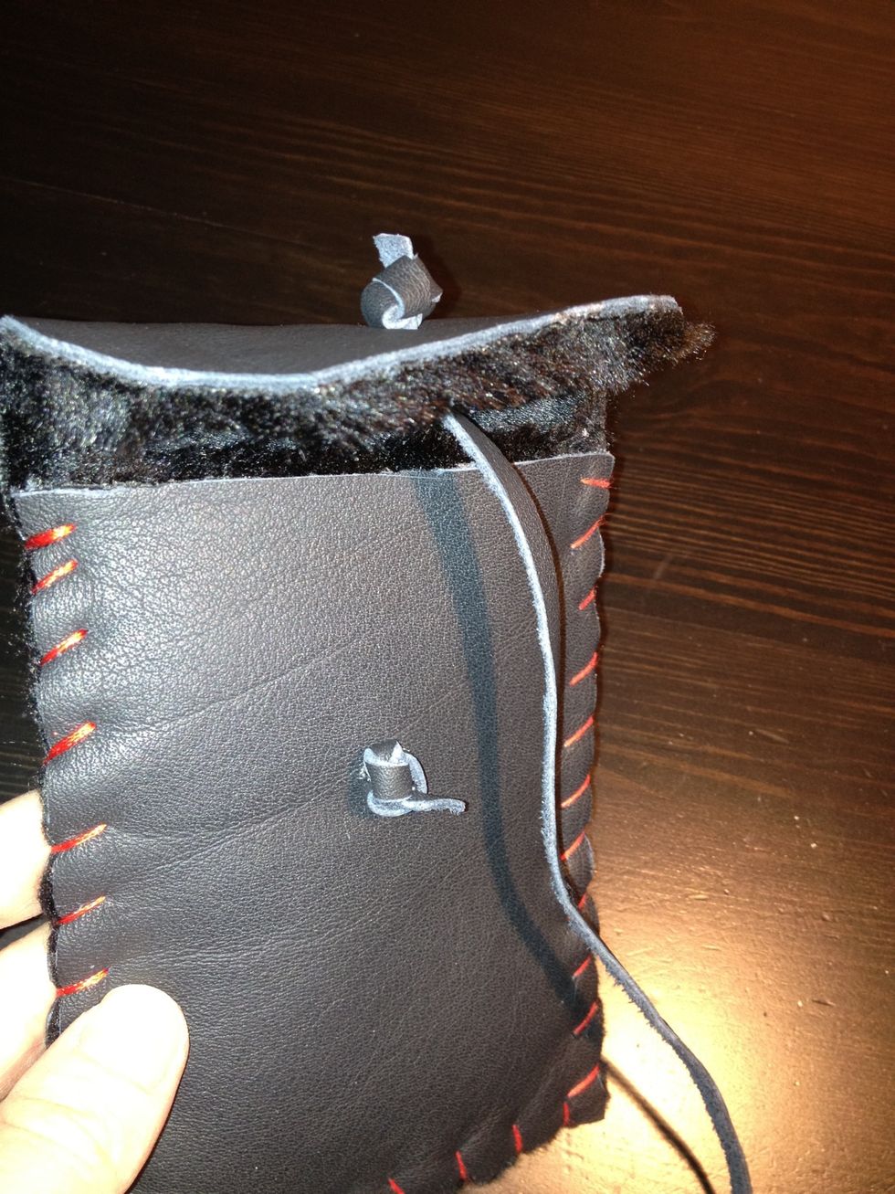 Tie a knot with the leather string on the top flap. Make another hole in the actual case and using more leather string, tie a knot once more.