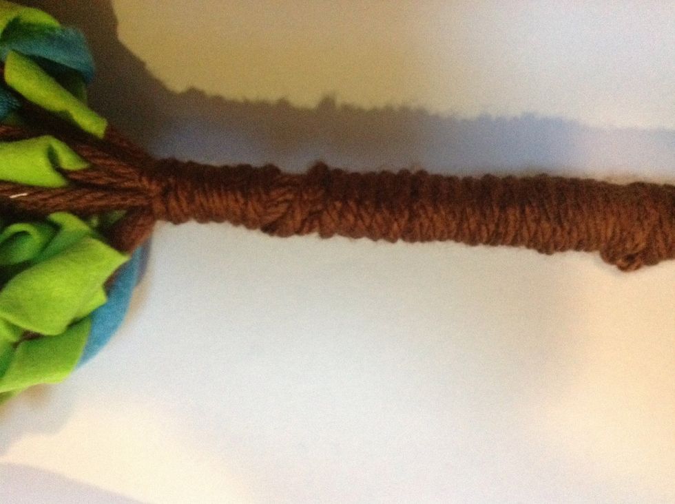 Tie a length of yarn with a double knot, around the top of the tree trunk. Wind it horizontally to the bottom of your trunk. If you run out of yarn, tie a new piece to the first and continue winding.