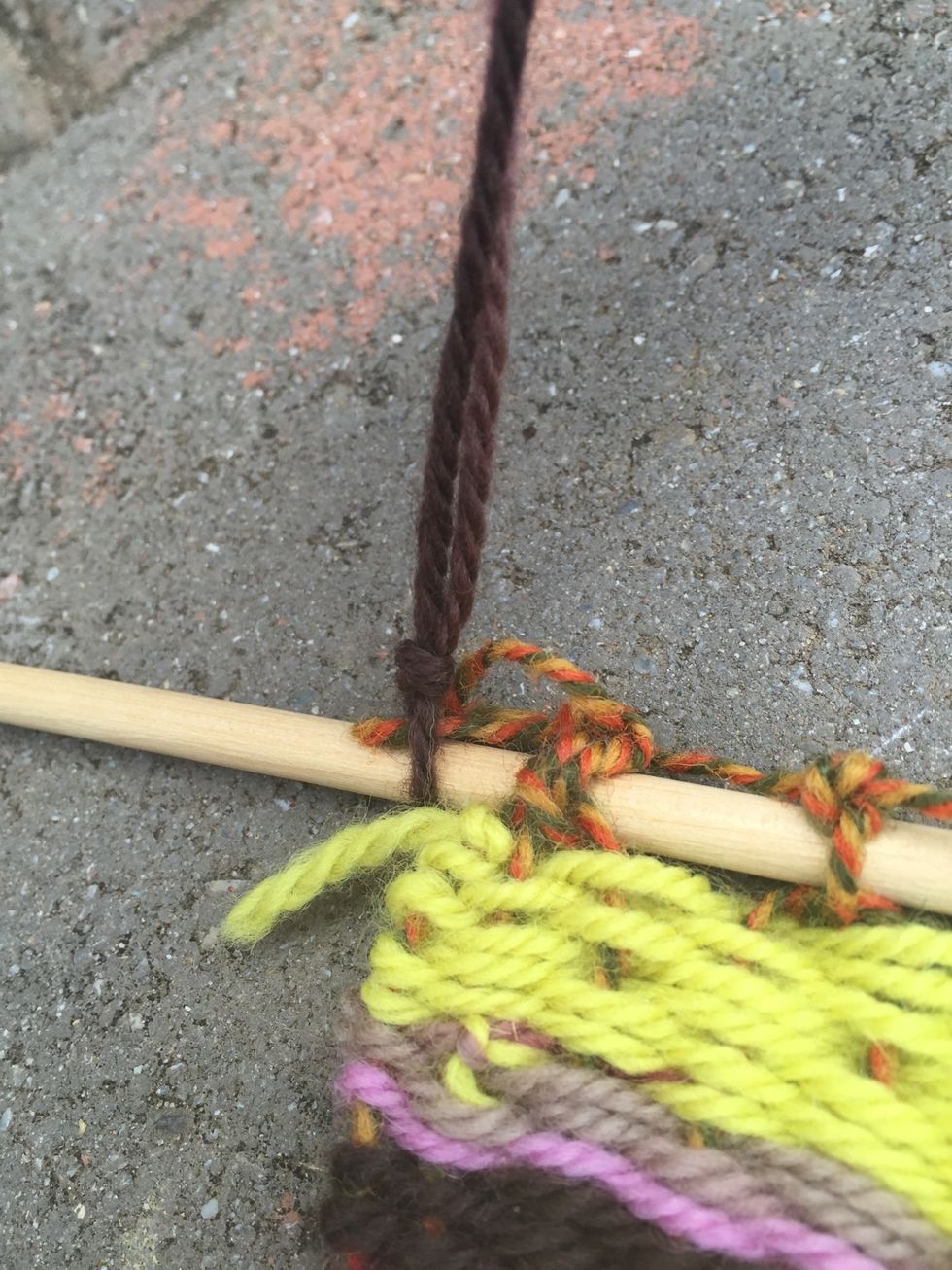 Tie a piece of yarn at each end of the top wooden dowel to hang your weaving on a wall.