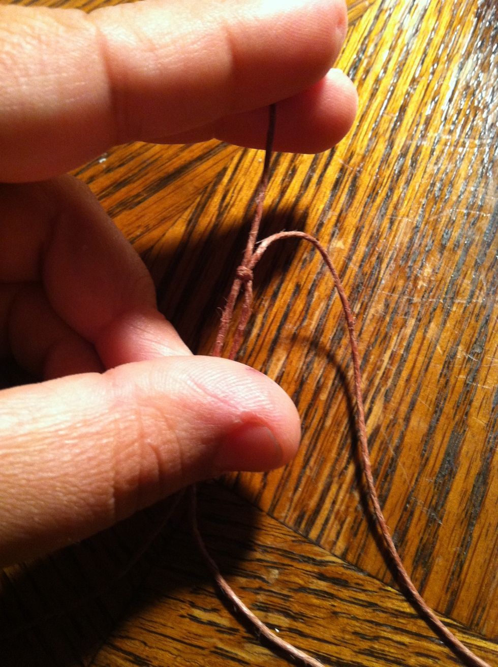 Tie a sliding knot with one string onto the other. Then repeat on the opposite string. ( next step is a video of how to tie a sliding knot)