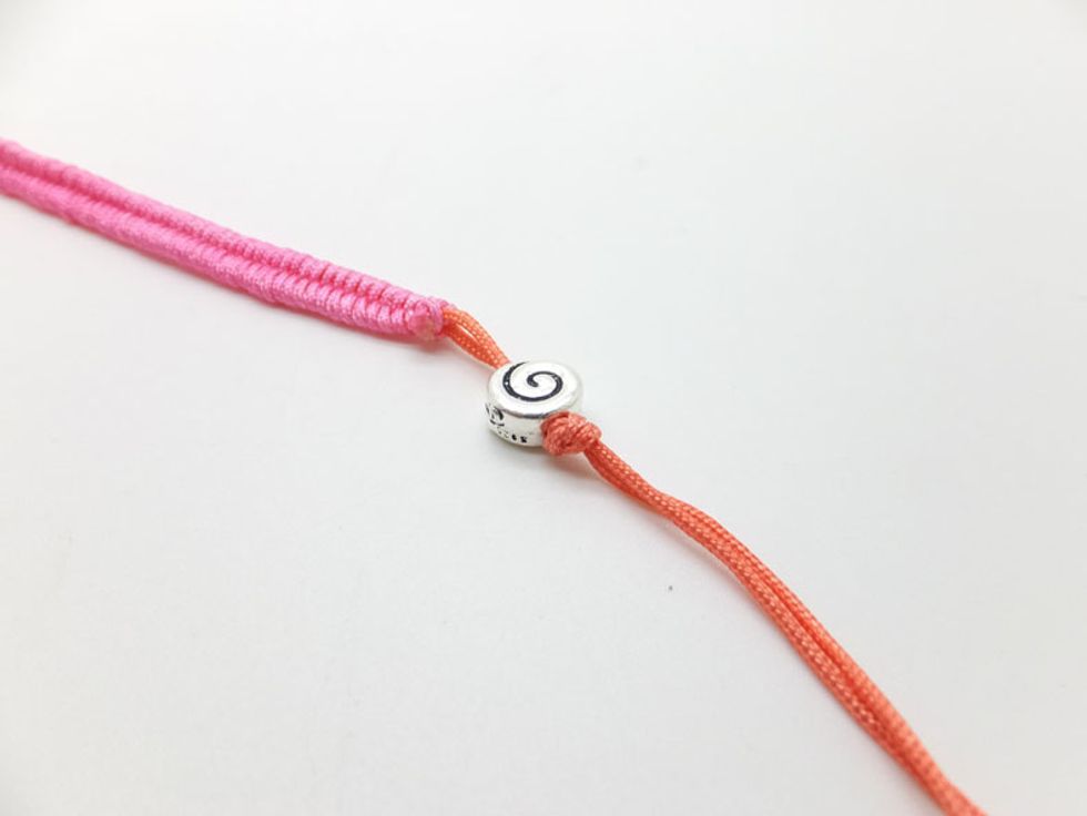 Tie an overhand knot after string the silver flat bead.