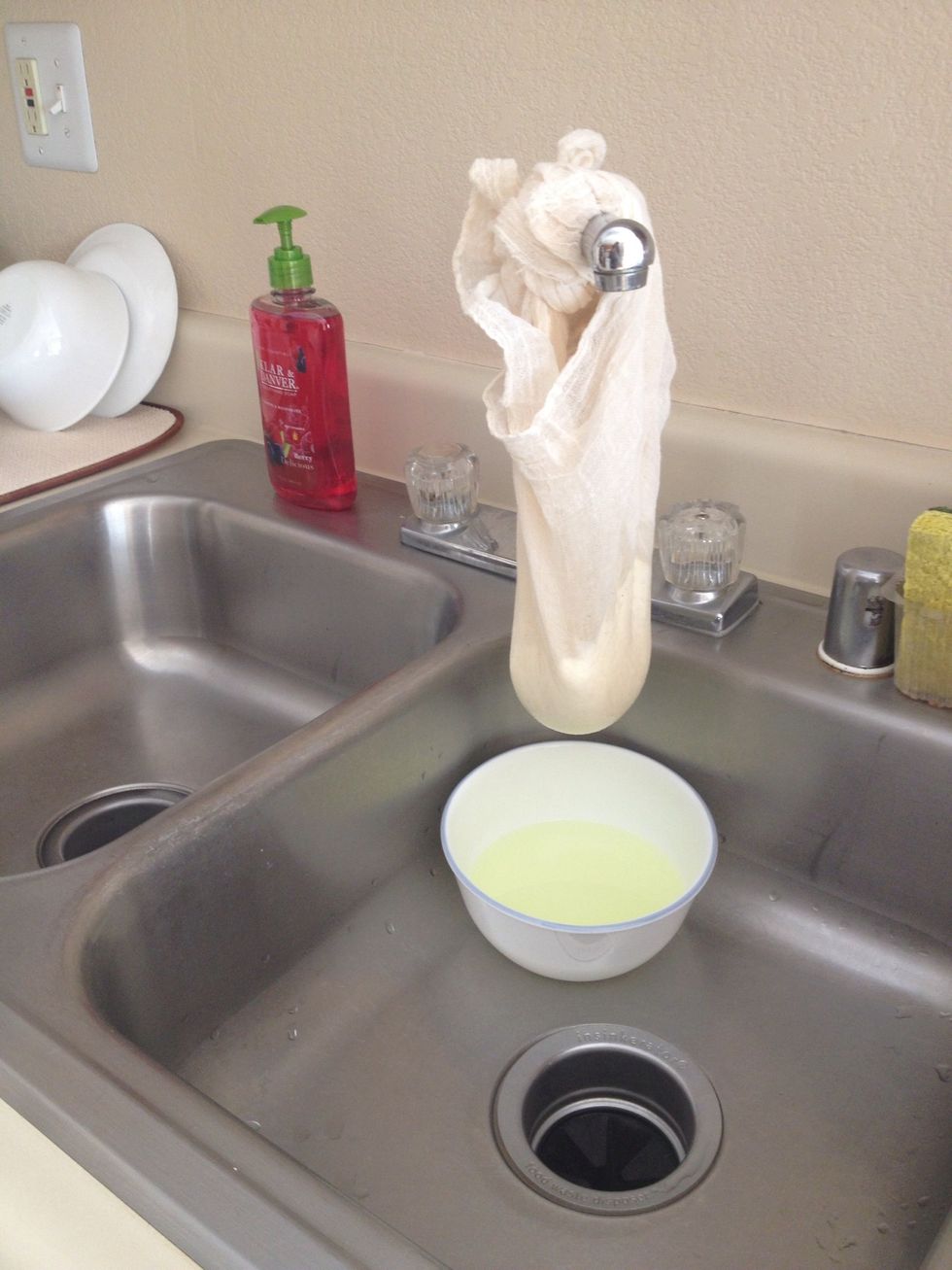 Tie the opposite corners of the cloth into a knot and hang over the sink on the faucet.