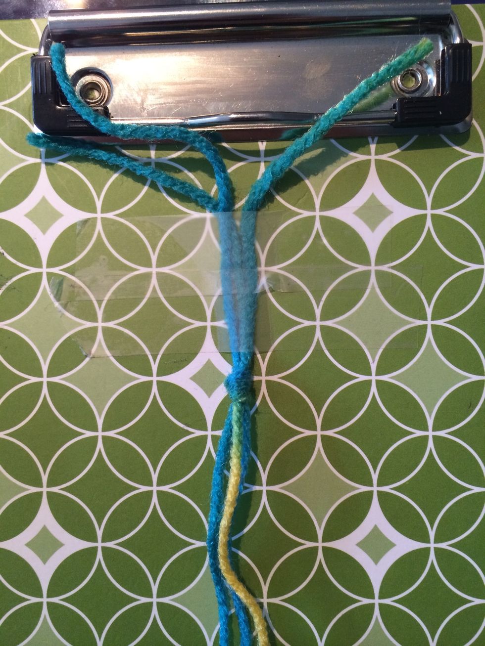 Tie your strings together and tape them to your surface. Leave about an inch to 2 inches to tie your bracelet together at the end.