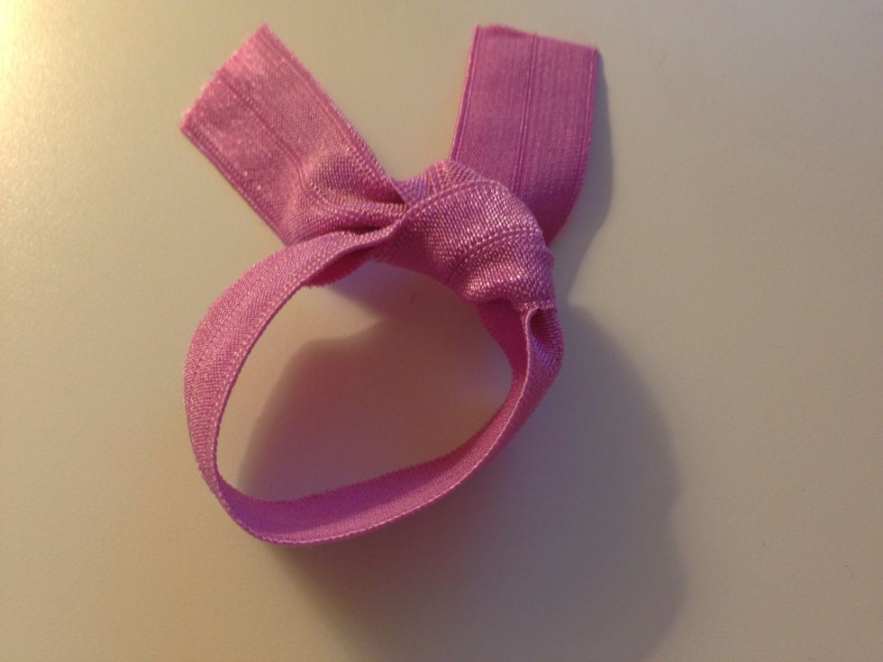 Tighten the knot by alternately pulling the ends and the middle of band. Before it gets too tight test it on your hair to your desired tightness. Then adjust as needed.