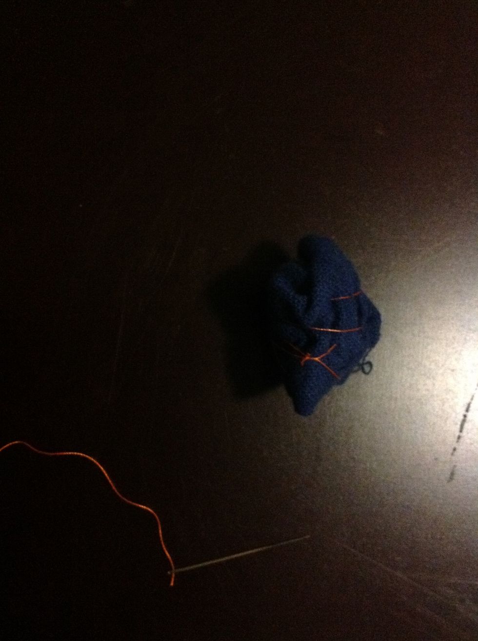 Tightly roll the cloth into a ball. Then pass the needle and thread through the ball multiple times until the thread is holding he ball in place. Tie off the thread.