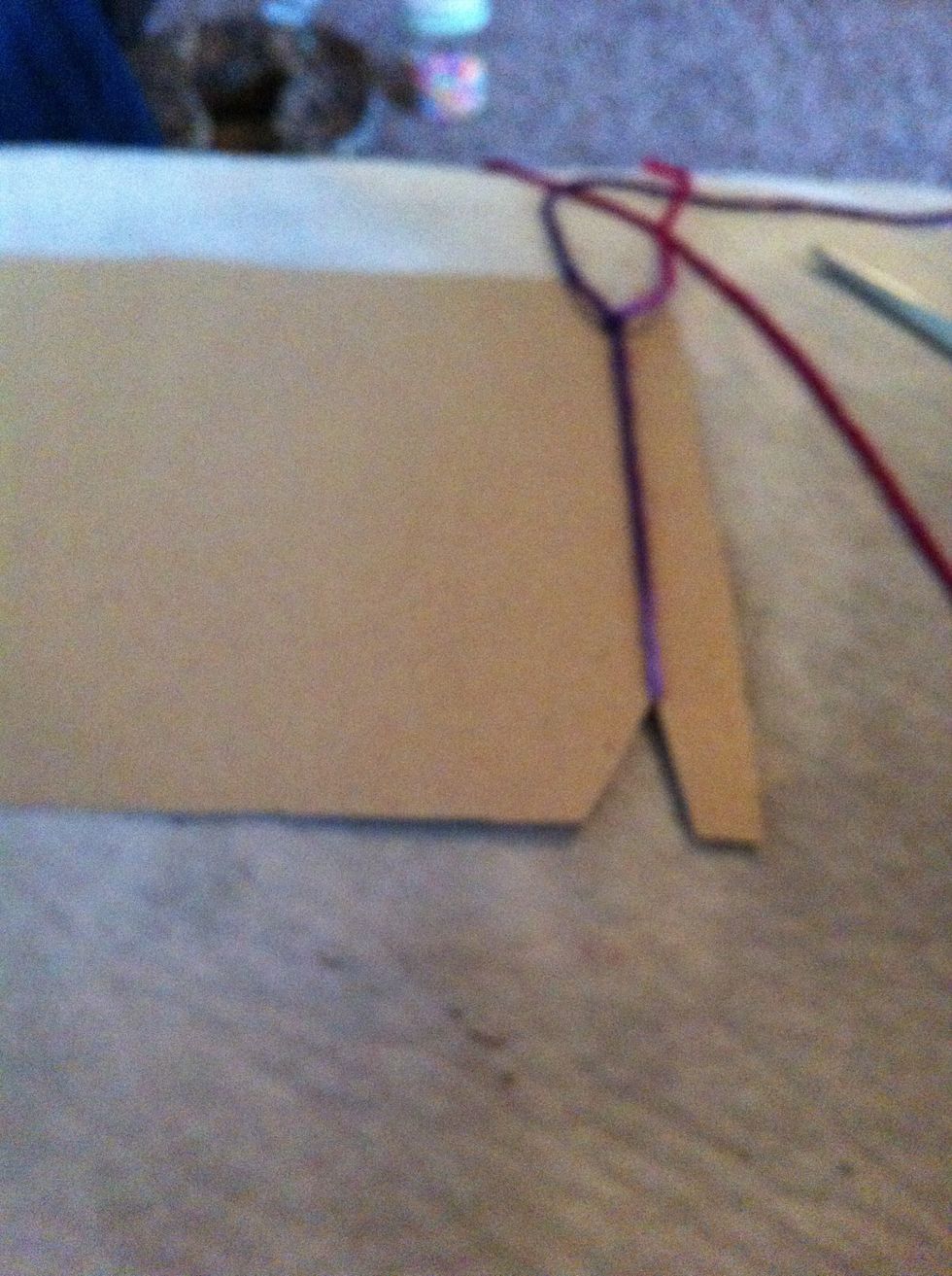 Tightly tie the end of your string to the end of the cardboard.