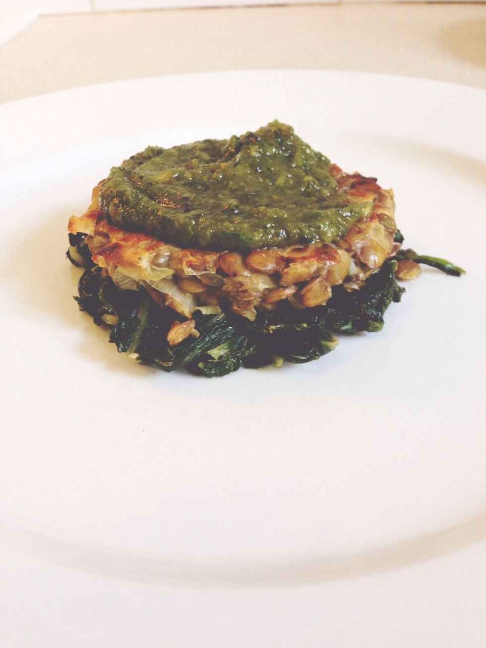 Time to assemble! Place some wilted greens at the bottom of plate, followed by a lentil patty and then a dollop of pesto. Repeat once more and add a handful of fries to top it off!