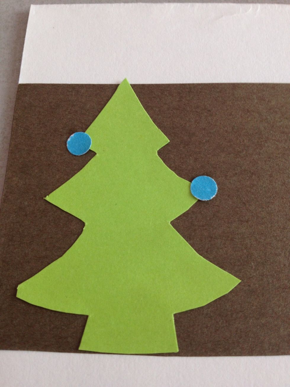 Time to decorate the tree! Hole punch the coloured paper to add ornaments to the tree. Glue down.