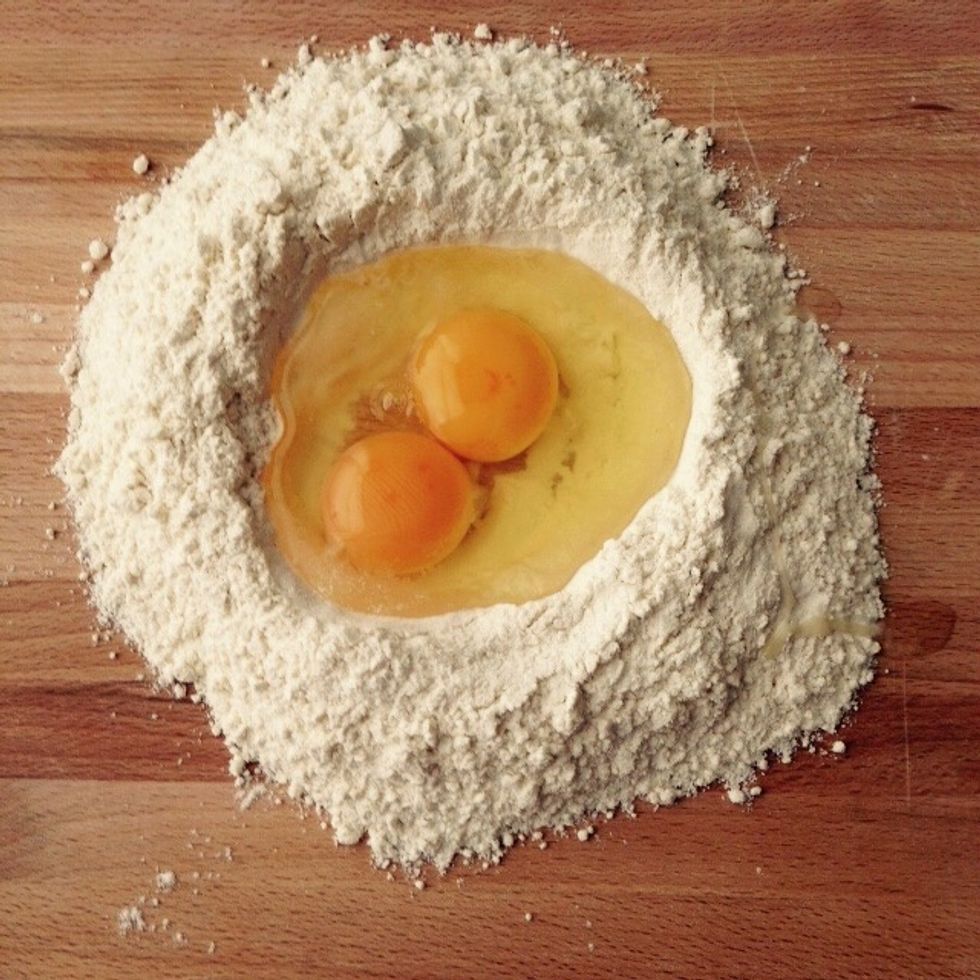 Time to make the dough for the pasta sheets. Make a pit of flour and crack the eggs in the middle.