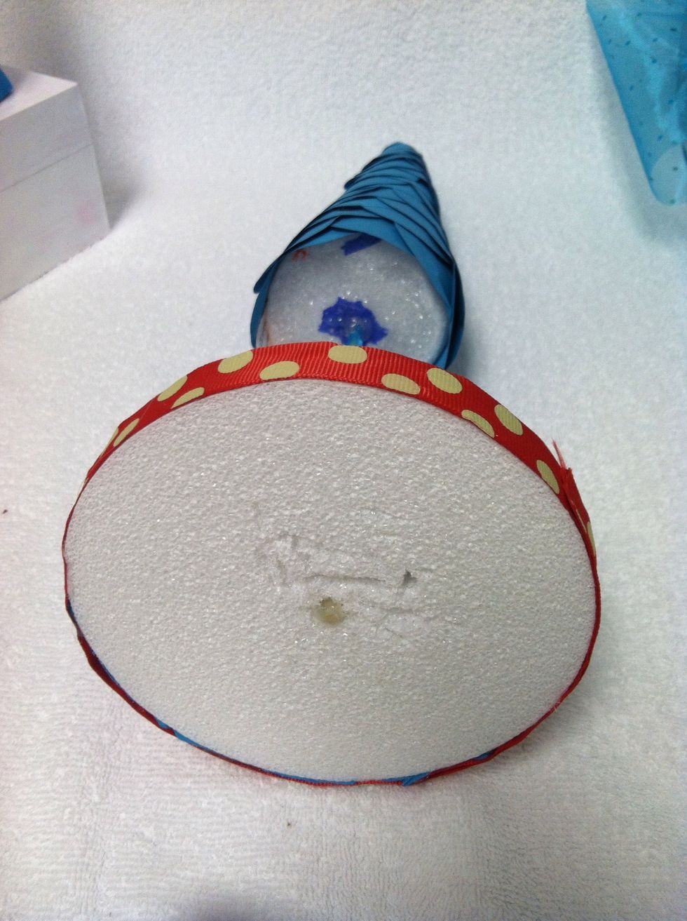 To add the base ribbon, place a string of hot glue to the edges and continue that all the way around. The ribbon should not hang over the bottom. .