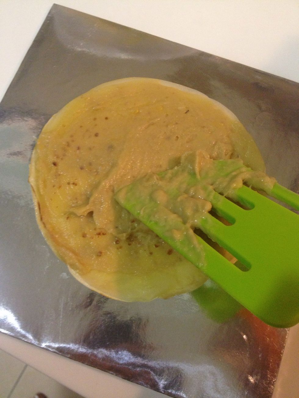 To assemble, lay a cr\u00eape on a plate. Pipe or use a spatula to completely cover the cr\u00eape with a thin layer of the cream.