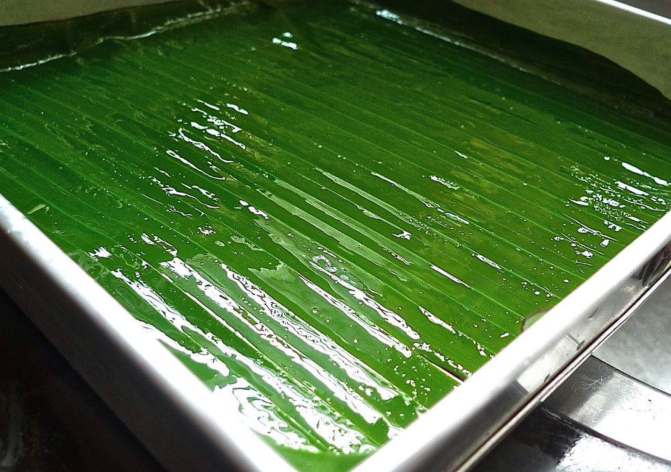 To bake tapioca cake, first line a 23 x 5 cm square cake tin with banana leaves, oiled on the shiny side. Otherwise use parchment paper.