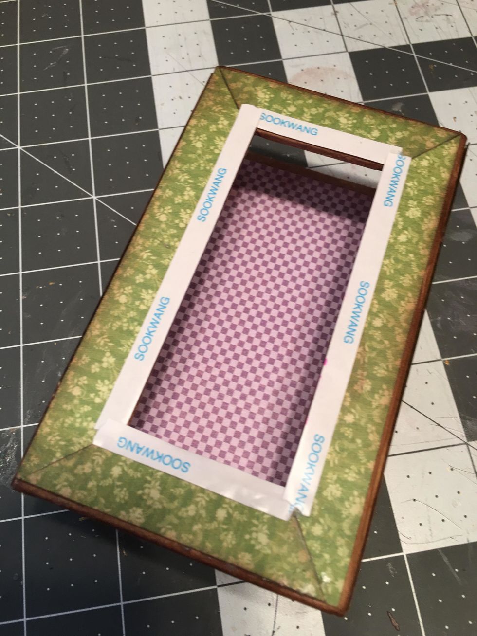 To begin decorating the lid, attach scor-tape around the perimeter of the opening as shown.