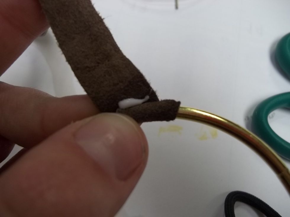To begin, wrap the suede strip around the hoop and apply a small amount of glue. Hold firmly, this will not hold at first, but will make the bond stronger once it's tied together.