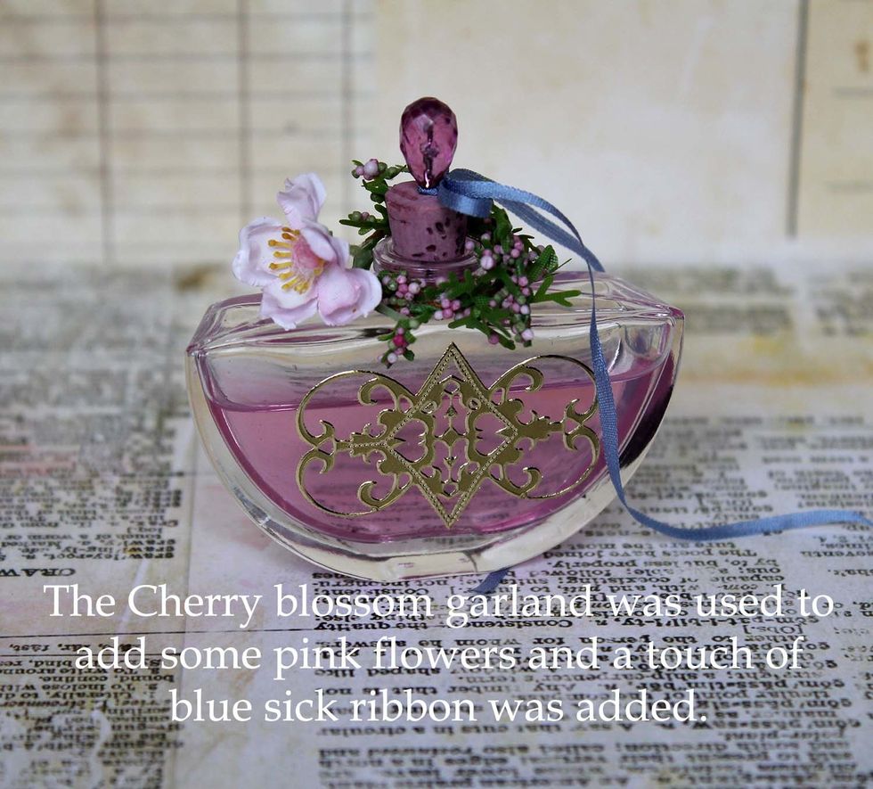 To finish the bottle I added a cherry (blossom) on top. Cut a piece from the garland and wrap around the bottle neck. Add a tiny blue ribbon to set it all off.