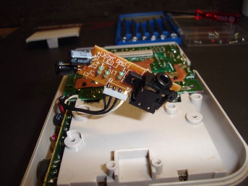 To fix the jack into the case you'll need to make a little more room. Use a mini-philips head screw-driver to remove the audio board with the headphone jack on it.