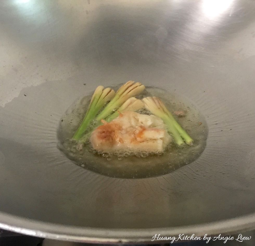 To fry, add cooking oil into a heated wok over medium low heat and saute the crushed lemongrass and galangal until fragrant.