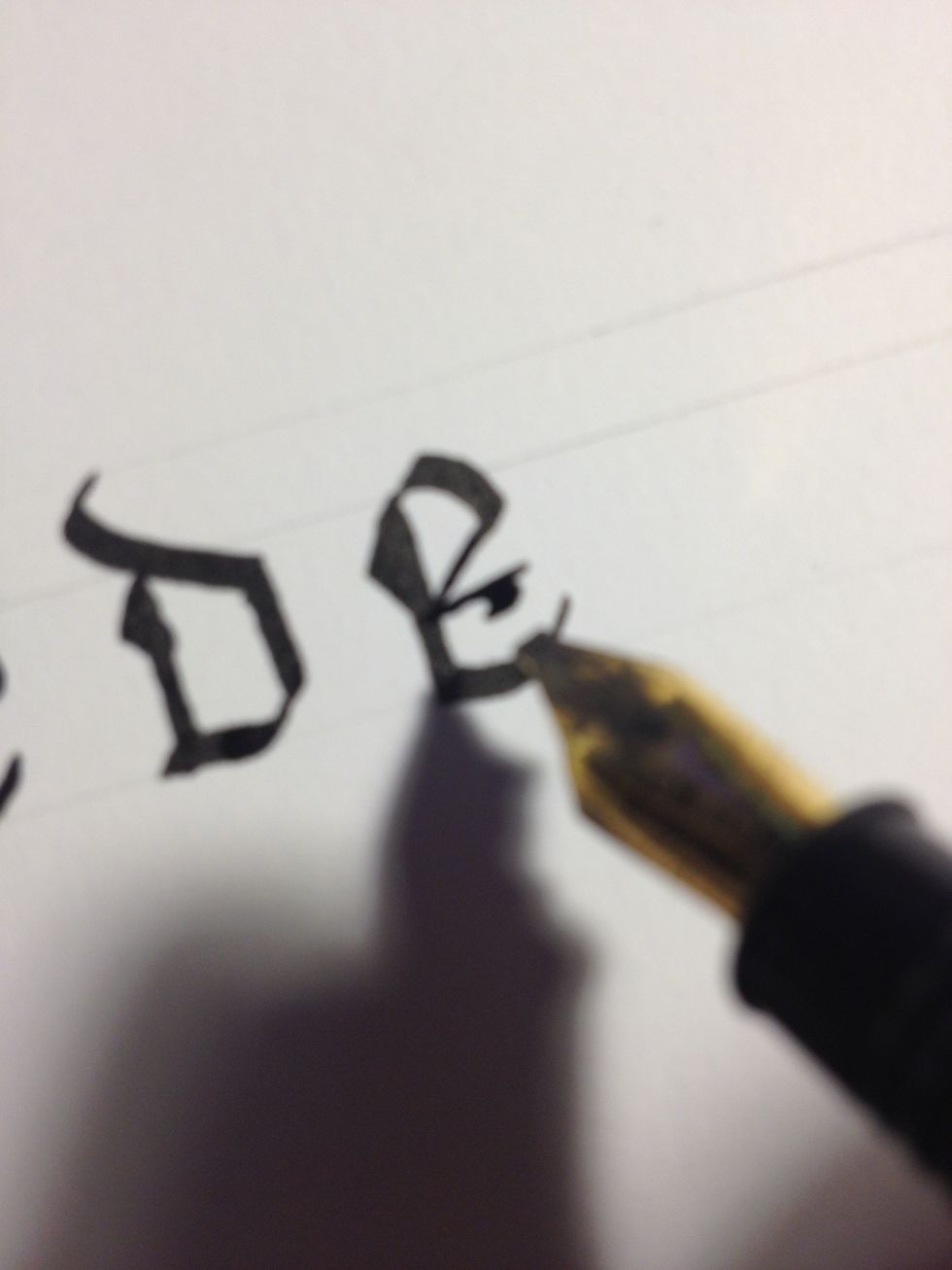 To further decorate the letter, rotate your nib so it is perfectly horizontal, then make a thin line out from the terminus of the previous stroke. Give this line a short, thick "tail".
