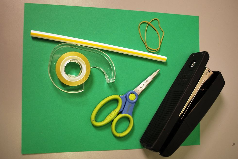 To get started you'll need paper, a staw, two rubber bands, scissors and a stapler.