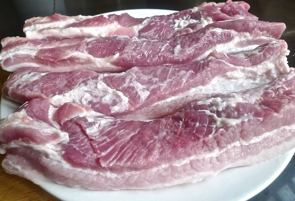 To grill Chinese barbecue pork, first rinse large strips of skinless pork belly, and pat dry.
