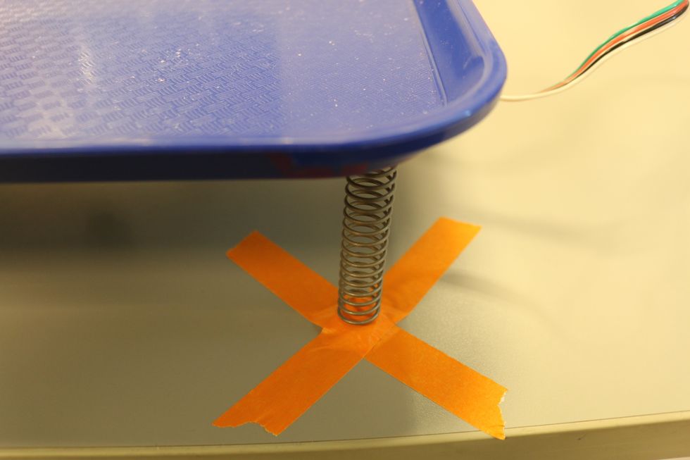 To keep the shake tray stay on the table, we tape down the four springs to the table. Suction cups could be attached to each spring to keep the tray in place.