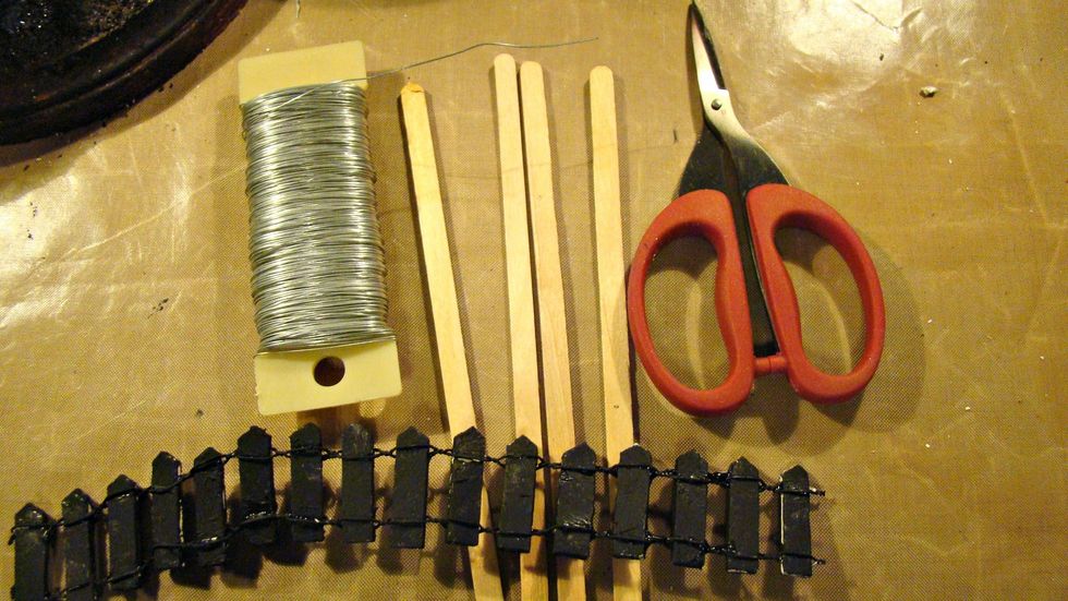 To make a rickety fence I took stir stick, cut them and pointed the tops and then attached them with floral wire. Paint with Tuxedo Black.