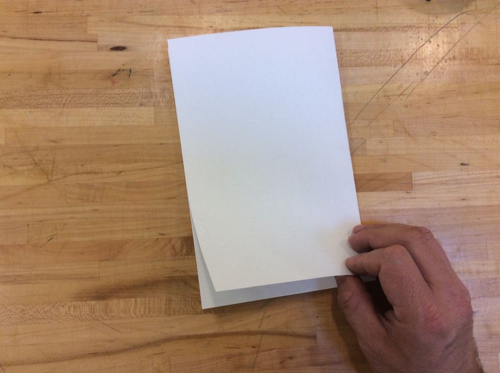 To make our pages that go inside of our cardboard cover, we start by folding one piece of paper in half (Hamburger Style).