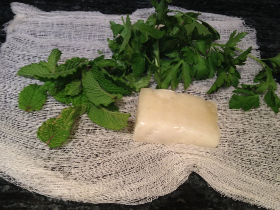 To make the bouquet garni, lay out a square of cheesecloth and place some sprigs of parsley, some mint, and a Parmesan rind in the center.