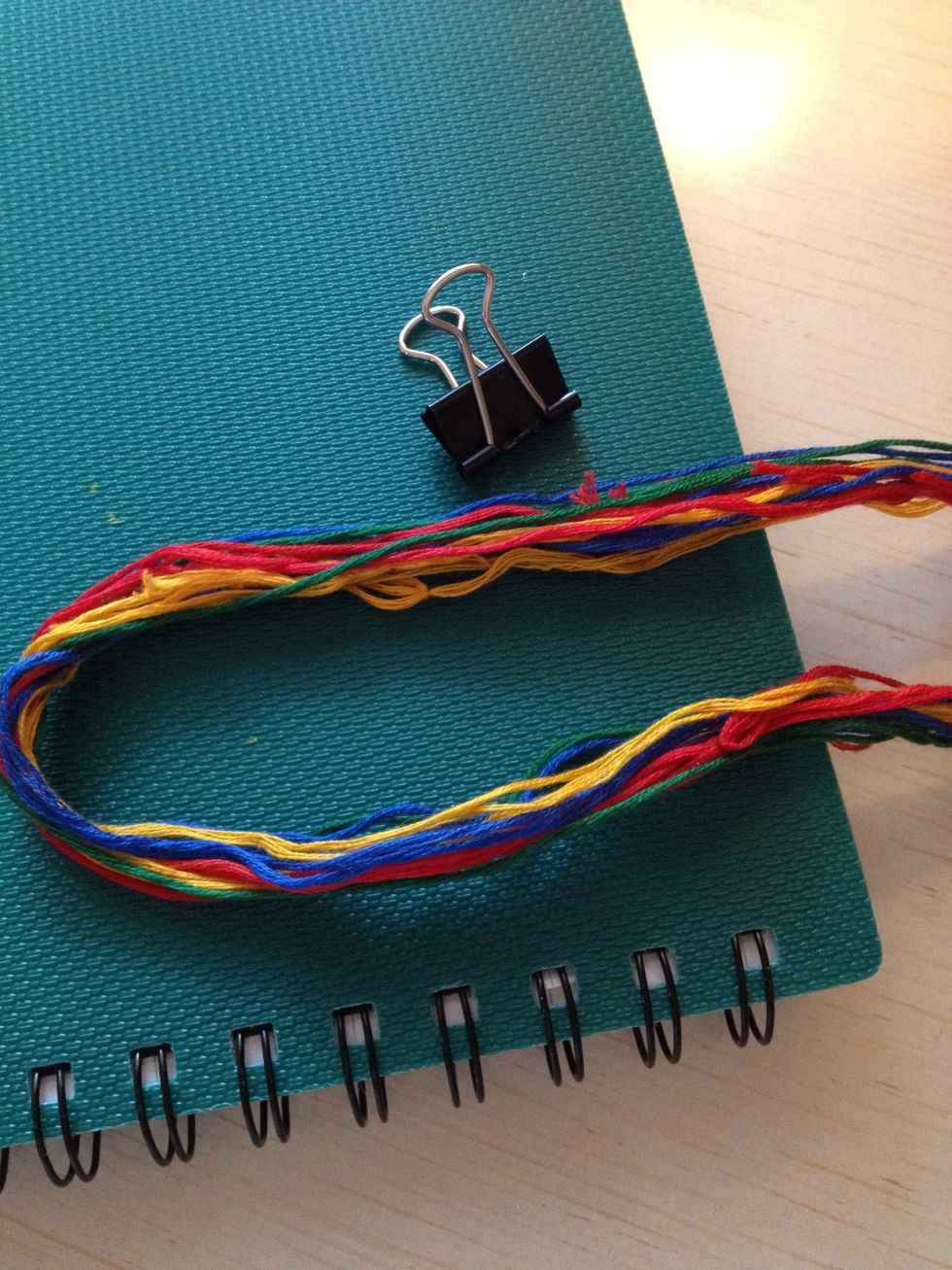 To make the bracelet you'll need yarn, a clip and a note book. For the Rhomb bracelet you'll need 16 threads: 4 blue/black, 4 green, 4 yellow and 4 red.