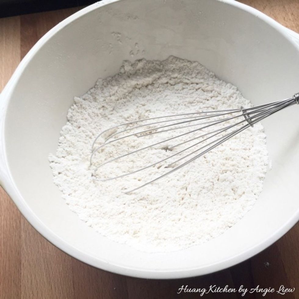 To make the crust pastry, first sift all-purpose flour, self raising flour and salt into a large mixing bowl. Using a whisk, mix everything together.