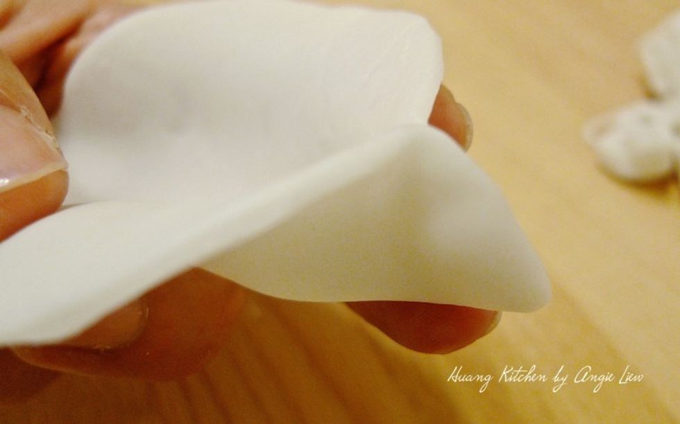 To make the dumplings, first fold the wrapper into a semi-circle, sealing slightly on one end.