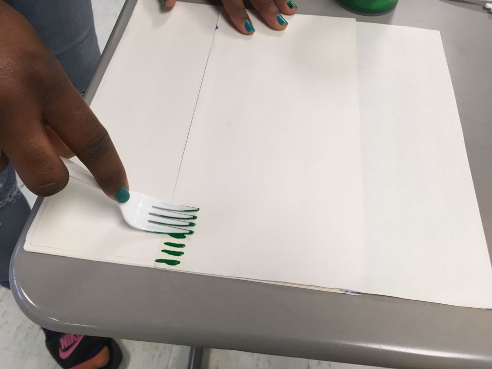 To make your grass, press the top of your fork with the paint at the bottom of the paper and slide it down to the edge.