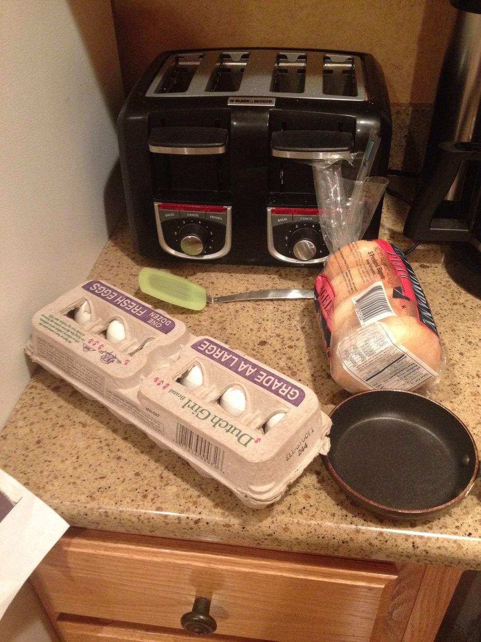 To make your very own egg mcmuffin, here are the items you will need, including eggs, bagels, a toaster, a spatula, cheese, and a frying pan!