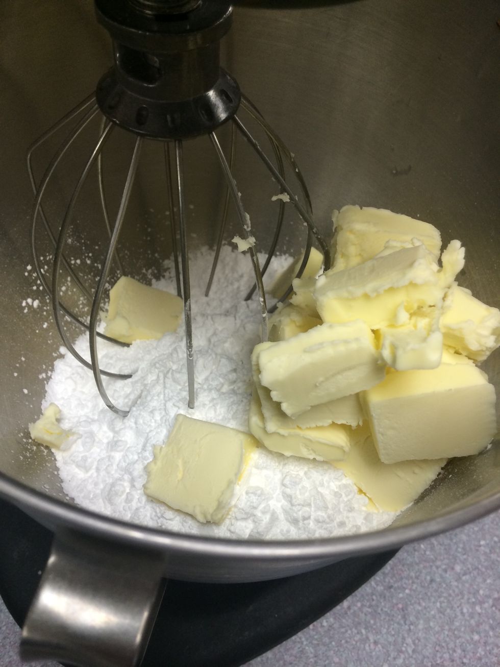 To start off your buttercream frosting, you want to put the butter chunks and confectioners' sugar into your Kitchen Aid and use the whisk attachment. Start on low and gradually increase the speed.