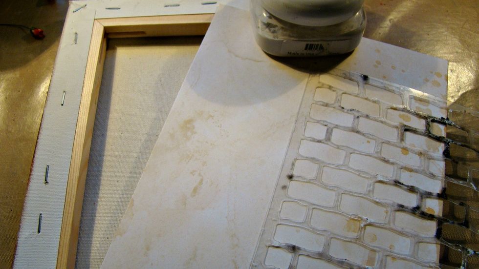 To start our canvas choose scrapbook paper for the inside, brick stencil and Mud Texture Paste. Cut your paper the size to fit the inside and stencil your bricks on the paper.