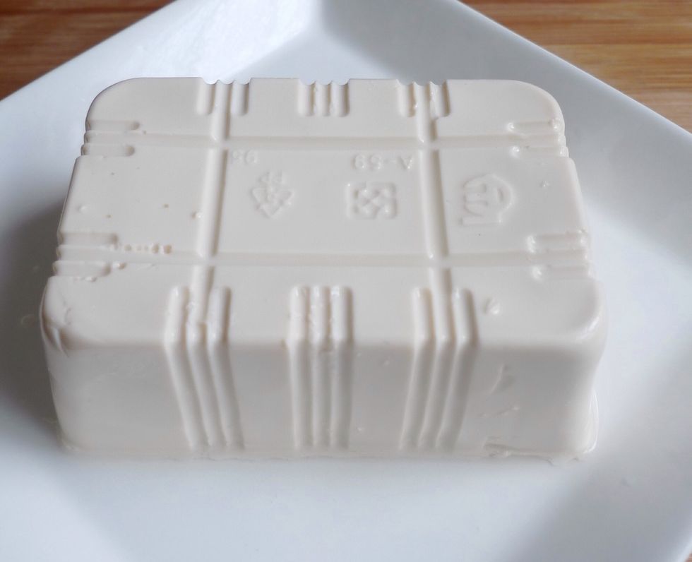 To steam the bean curd with hot shallot oil, first place a block of plain, soft bean curd on a steaming plate.