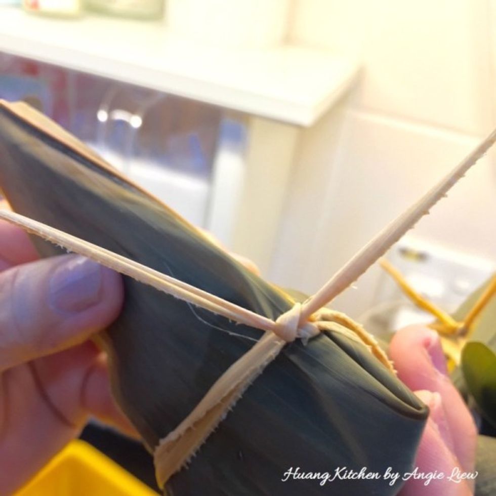 To tie the dumpling, wrap it with the bamboo string twice, each time with an easy knot to ensure no loose ends. Tie the dumplings in groups of ten and we're now ready to cook them.