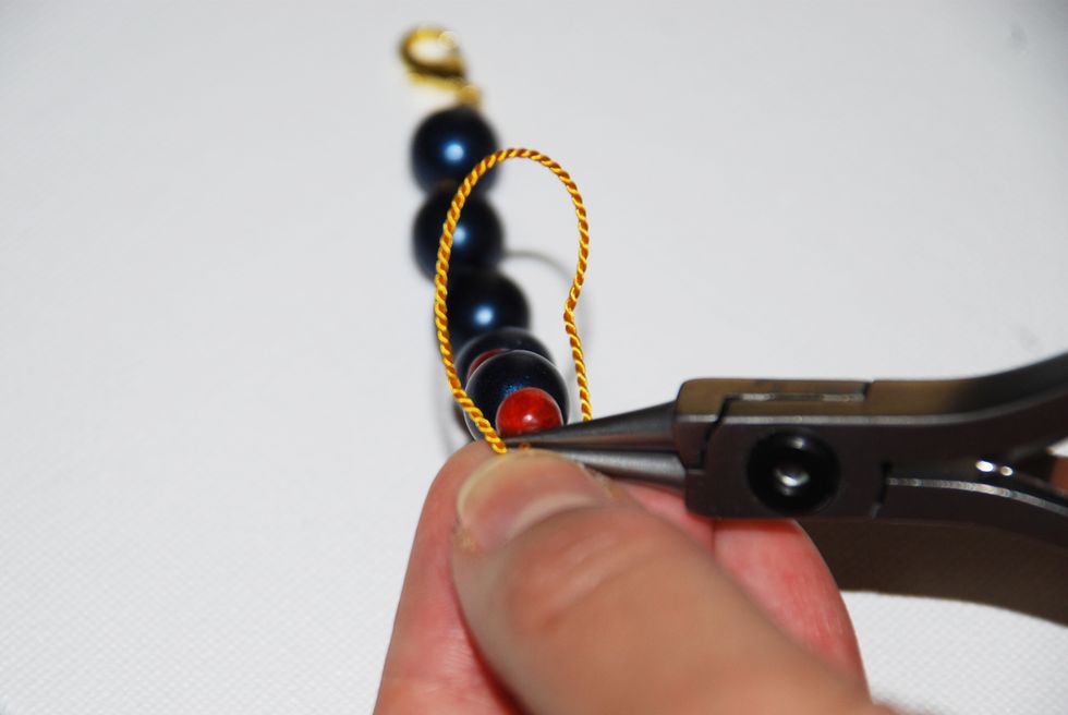 To tighten the knot, grab the thread inside the loop with the tip of your round nose pliers. Remember to keep the tip of your tool as close to the stone as possible to keep your knot neat.