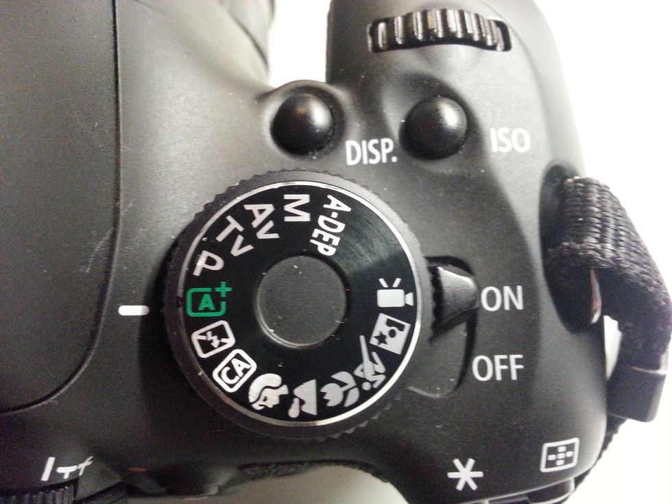 To turn on the camera, flip the switch next to the Mode Dial to ON. Turn the Mode Dial until the green "A" (Automatic) symbol is next to the white line.