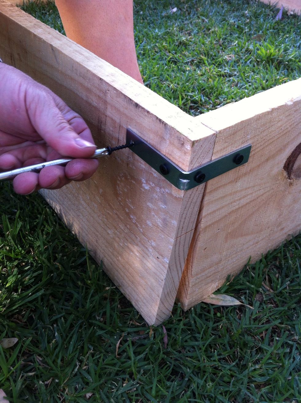 Tomar dos tablones y unirlas colocando dos escuadras de metal en cada esquina. Puedes usar la ayuda del martillo./ Take 2 panels of wood and attach them with two metal brackets. Can use hammer's help