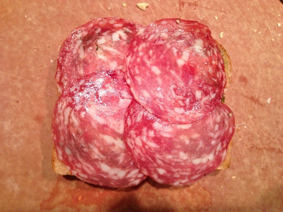 Top cheese and pesto with salami